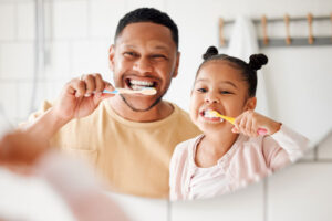 Child, dad and brushing teeth in a family home bathroom for dental health and wellness in a mirror.